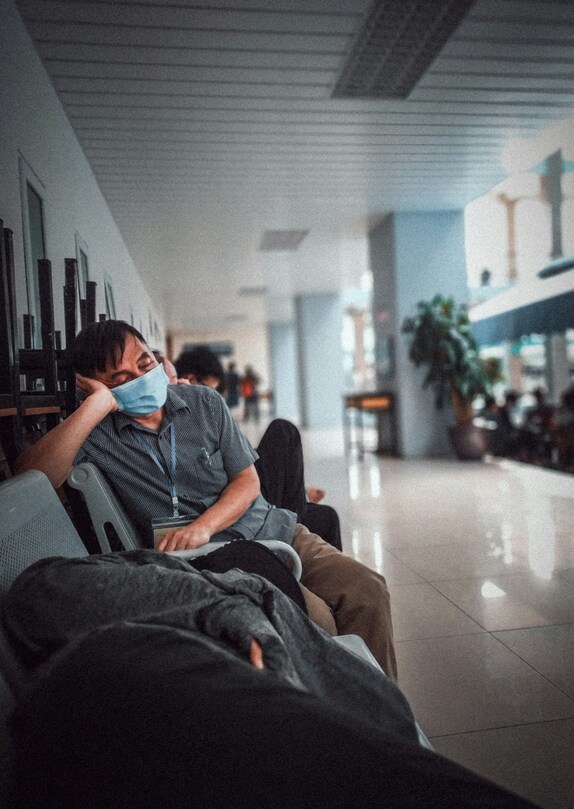 homem sentado esperando no hospital com mascara na boca